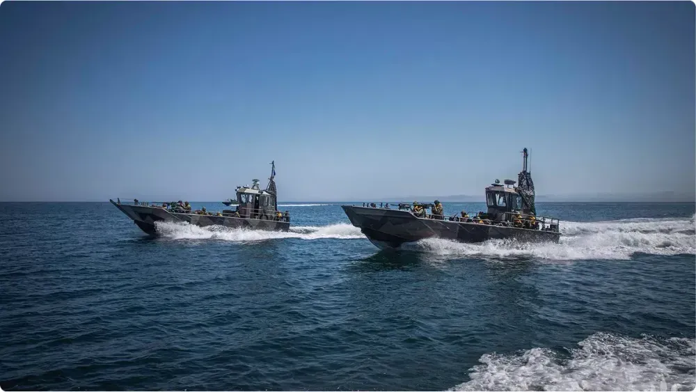 Два бойові катери Військово-Морських Сил України йдуть на високій швидкості відкритим морем. На носі кожного видно кулемети та бійців у формі, за кормою залишається слід білої піни, на кабіні одного з катерів — маскувальна сітка.